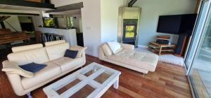 a living room with two white couches and a tv at Jack's Lodge - La Grange in Tosse