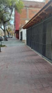 una acera de ladrillo junto a un edificio con una valla en Departamento Aristobulo en La Cieneguita