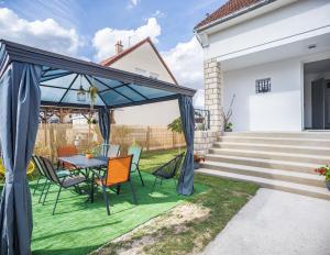 een patio met een tafel en stoelen op het gras bij Le Flamboyant - Confort & Rareté - Premium in Saint-André-les-Vergers