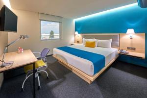 Habitación de hotel con cama grande y escritorio. en City Express by Marriott Suites Toluca, en Toluca