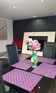 einen Tisch mit lila Servietten und eine Vase mit Blumen darauf in der Unterkunft Hollidays home piscine et jardin in Plan-de-Cuques