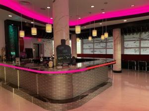 a bar in a restaurant with pink lighting at The Streamline Hotel - Daytona Beach in Daytona Beach
