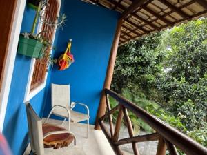 a balcony with two chairs and a blue wall at Vivendas do Serrano Apart105 Lençois in Lençóis