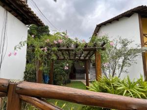 a wooden pergola with pink flowers on a house at Vivendas do Serrano Apart105 Lençois in Lençóis