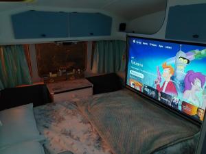 a bedroom with a large screen on a bed at Cosy private Glamping with Pizza stove, Big Projector Screen, own hot Monsoon shower, breakfast - Glamping with a difference! in Tenby