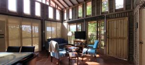a living room with chairs and a tv and windows at Cabaña en El Guadual in Santandercito