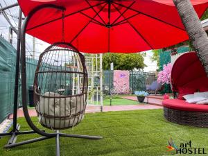 una jaula de pájaro rojo sentada bajo un paraguas rojo en Art Gardens Wynwood concept en Miami