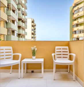 2 sedie e un tavolo con fiori sul balcone di Kalbia Apartment Renovated, functional, intimate and more a Cagliari