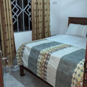 a bedroom with a bed with a blanket on it at Mufasa city Hostel and Apartments in Arusha