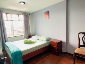 1 dormitorio con 1 cama con ventana y silla en CASA DEL ARBOL ESCAZU en San Antonio