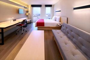 a hotel room with a bed and a desk and a couch at City Express by Marriott Monterrey Universidad in Monterrey