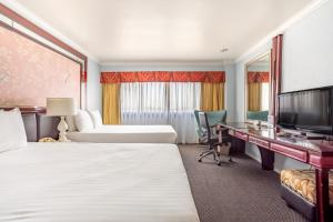a hotel room with two beds and a desk and a television at Hotel Koxie in Los Angeles