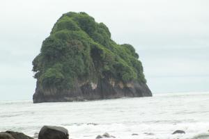 a small island in the ocean with the waves at La Aldea del Primitivo in Nuquí