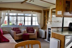 a living room with a couch and chairs and a fireplace at Cosy Cottage Caravan in Ashington