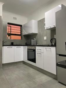 Urban & Comfortable Loft apartment in Mthatha في امتاتا: مطبخ كبير مع دواليب بيضاء ونافذة