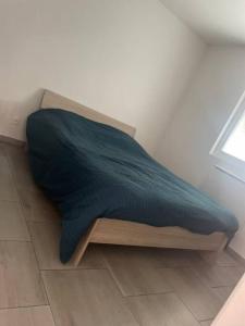 een bed met een blauwe deken op de vloer naast een raam bij L'eSPAce détente in Beuvry