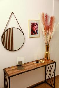 una mesa con espejo y un jarrón con plumas. en Edem House en Volos