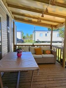 a patio with a couch and a table on a deck at mobil-home neuf 4-6 places camping Siblu les viviers in Lège-Cap-Ferret