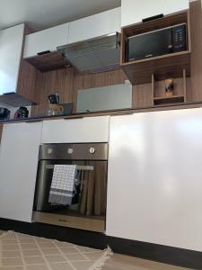 a kitchen with a stove and a microwave at mobil-home neuf 4-6 places camping Siblu les viviers in Lège-Cap-Ferret