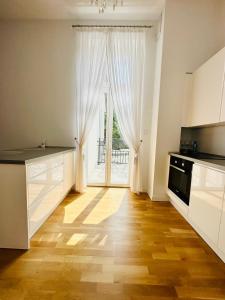 a kitchen with white cabinets and a large window at Apartament MARILYN w Kamienicy Wicherkiewiczów in Poznań