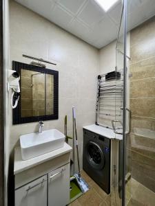a bathroom with a sink and a washing machine at Dushanbe City View Apartment in Dushanbe