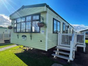 a green tiny house with a staircase and windows at Cosy Cottage Caravan in Ashington