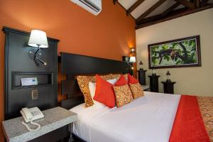a hotel room with a bed with a phone on it at Hotel Arenal Springs Resort & Spa in Fortuna