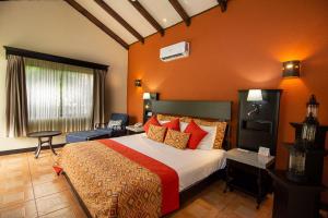 a bedroom with a large bed with orange walls at Hotel Arenal Springs Resort & Spa in Fortuna