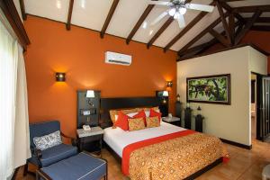 1 dormitorio con 1 cama y 1 silla en Hotel Arenal Springs Resort & Spa en Fortuna