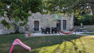 a stone house with a table and chairs in a yard at Maison de Vacances 12min du Puy du fou grand studio in Saint-Laurent-sur-Sèvre