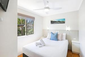 a bedroom with a large white bed with blue pillows at Reflections Tuncurry - Holiday Park in Tuncurry