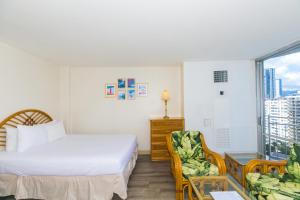 Un dormitorio con una cama y una silla y una ventana. en Ilikai Marina 1495 City View Studio, en Honolulu