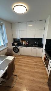 a kitchen with white cabinets and a table in a room at Apartman City Park Stráňany in Michalovce