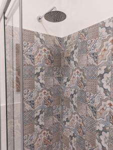 a shower with a glass door and a mosaic tile wall at Appartamento Piazzetta La Maddalena in Savona