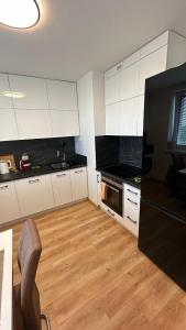 a kitchen with white cabinets and a wooden floor at Apartman City Park Stráňany in Michalovce