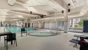 a large pool with a table and chairs in a building at El Tesoro in the Heart of Van w/ Air Con, Pool, and Free Parking in Vancouver