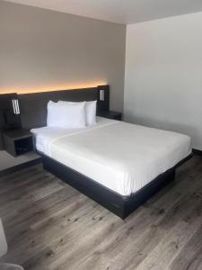 um quarto com uma cama grande e lençóis brancos em Motel 6-Orlando, FL - Winter Park em Orlando