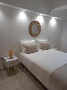 a white bedroom with a large bed and a mirror at Helena's House in Nazaré