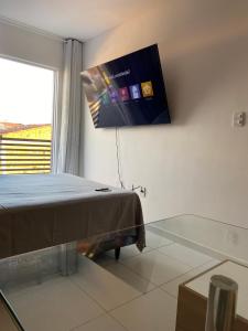 a bedroom with a bed and a tv on the wall at Flat em Campina Grande in Campina Grande