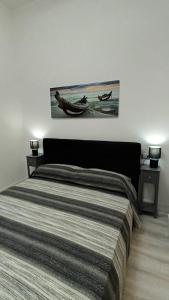 ein Schlafzimmer mit einem Bett mit zwei Nachttischen und einem Bild in der Unterkunft La Laguna Rooms in SantʼAntìoco
