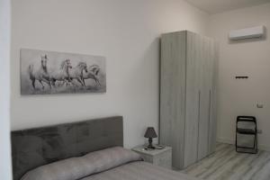 1 dormitorio con 1 cama y una foto de caballos en la pared en La Laguna Rooms, en SantʼAntìoco