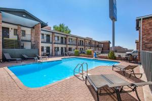 - une piscine avec une table et des chaises en face d'un bâtiment dans l'établissement Best Western Arizonian Inn, à Holbrook