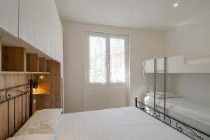 a white bedroom with a bunk bed and a window at Casa Casui in Ventimiglia