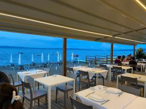 a restaurant with white tables and chairs and the ocean at Villa Bel Lago in Bracciano