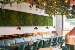 a restaurant with tables and chairs and a green wall at Scandic Frankfurt Hafenpark in Frankfurt/Main