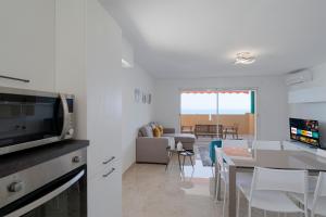 eine Küche und ein Wohnzimmer mit einem Tisch und einer Mikrowelle in der Unterkunft La Rose des Vents - Sea View in Roquebrune-Cap-Martin