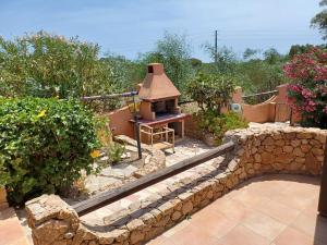 un giardino con muro in pietra e forno in mattoni di Casa Evalù a Pula