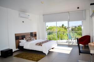 a white bedroom with a bed and a large window at SeaSide Hotel in Puerto Baquerizo Moreno