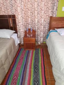 una habitación con 2 camas y una mesa con bebidas. en hostal andina joya, en Puno