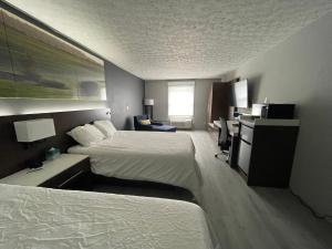 エルキンズにあるLuxor Inn & Suites, a Travelodge by Wyndhamのベッド2台とデスクが備わるホテルルームです。